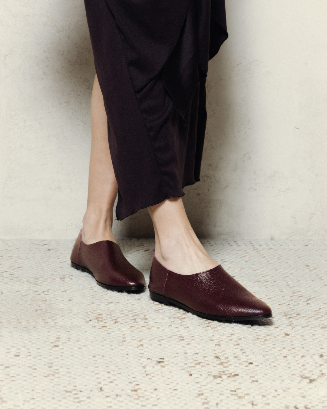 Person wearing dark purple loafers and holding a matching handbag  - Thuna - KSA